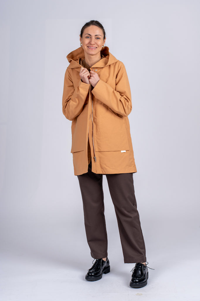 Moteriškas camel spalvos lietpaltis su minimalistiniu dizainu, su dviem kišenėmis, puikiai tinkantis miesto stiliui, nuotraukoje modelis iš priekio atsegtu paltu