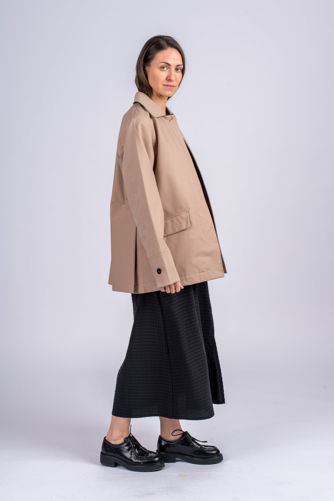 Šviesiai rudos spalvos minimalistinio dizaino moteriškas švarkas/striukė elegantišku tiesiu siluetu, užsagstoma kniedėmis, nuotraukoje modelis su atsegtu švarku iš šono