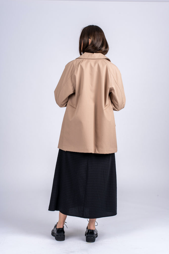 Pastelinės žalios spalvos minimalistinio dizaino moteriškas švarkas/striukė elegantišku tiesiu siluetu, užsagstoma kniedėmis, nuotraukoje modelis su atsegtu švarku iš nugaros