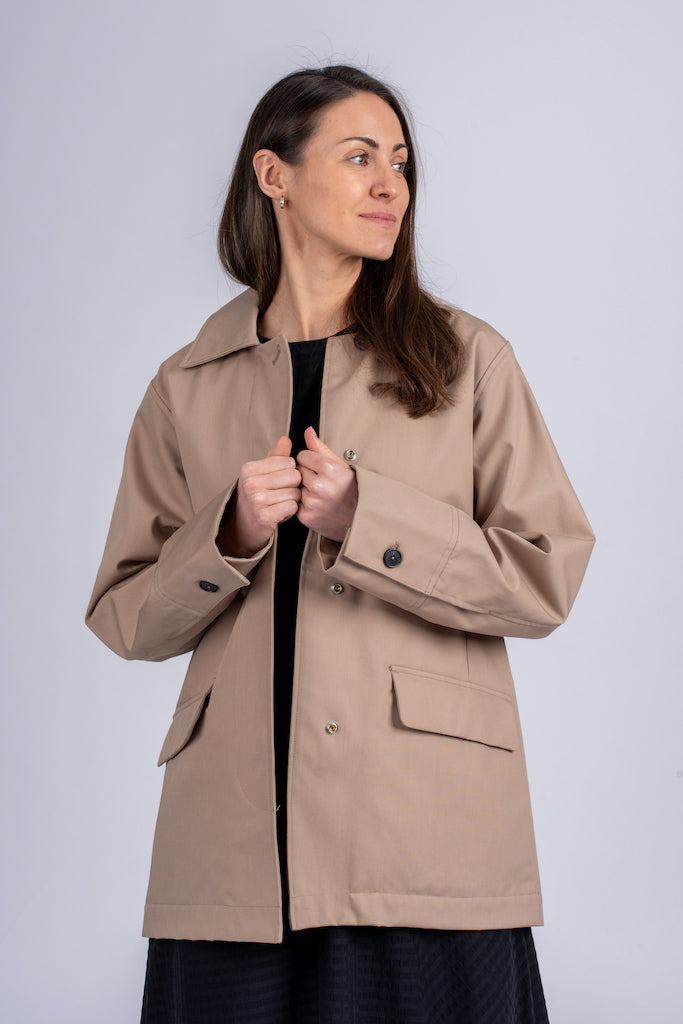 Pastelinės žalios spalvos minimalistinio dizaino moteriškas švarkas/striukė elegantišku tiesiu siluetu, užsagstoma kniedėmis, nuotraukoje modelis su atsegtu švarku iš priekio