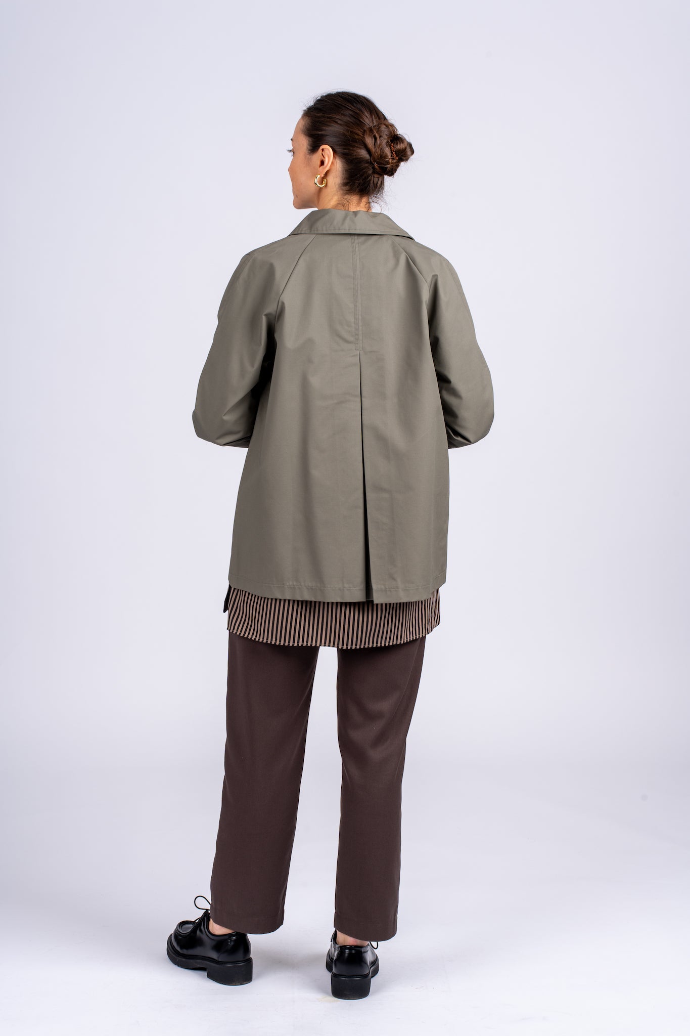Klasikinis oversized tipo švakelis/striukė camel spalvos, vidutinio ilgio, subtiliai maskuoja sėkmenis ir suteikia kasdieniai išvaizdai modernios klasikos įvaizdį, nuotraukoje modelis iš galo, matosi striukės skeltukas